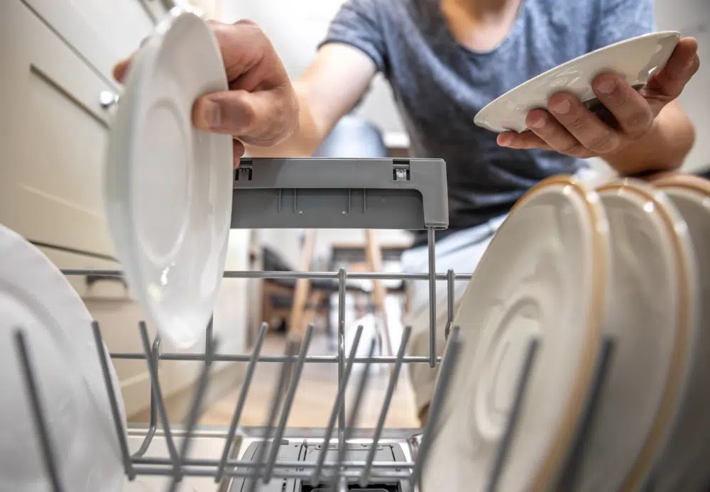 man-front-open-dishwasher-takes-out-clean-dishes-after-washing